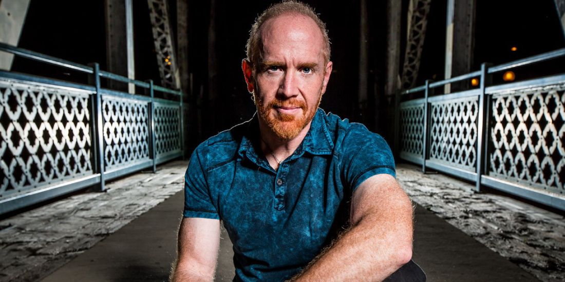 Close-up portrait of musician Mike Massé sitting on an outdoor bridge at night.