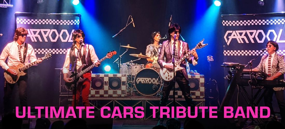 The band Carpool performing live on a concert stage with blue spotlights, featuring two large checkered backdrop banners bearing their logo, full stage instrumentation, and pink text at the bottom reading "Ultimate Cars Tribute Band."
